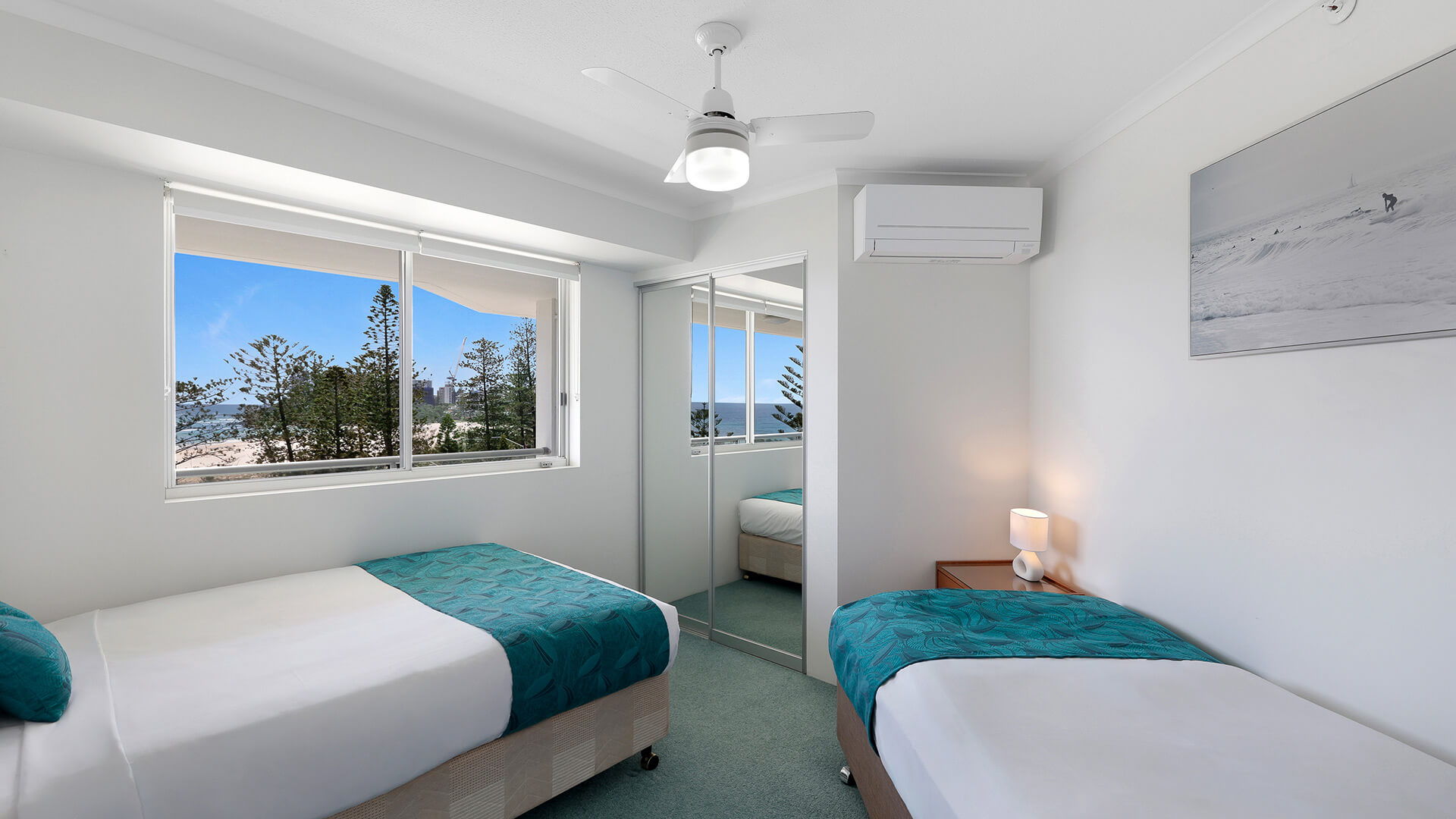 Twin bedroom featuring ocean views, mirrored wardrobes, and airy coastal styling.