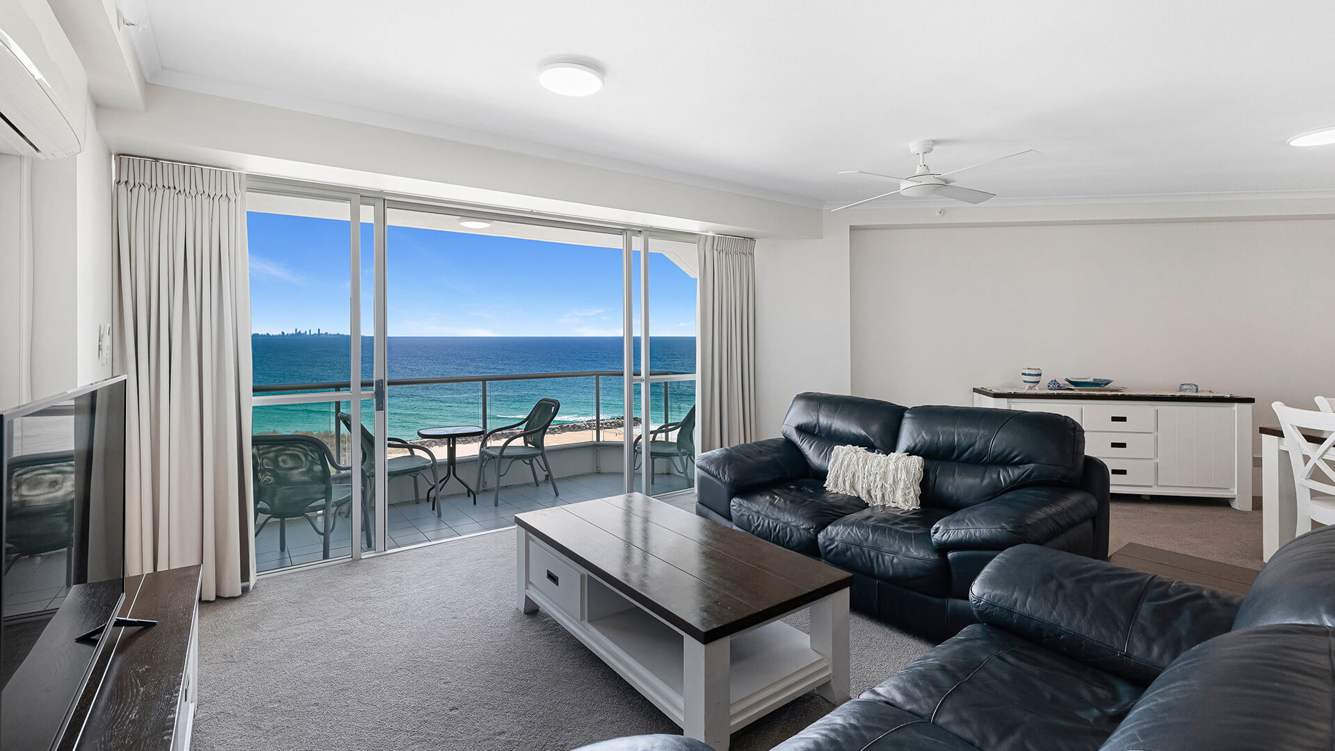 Spacious living area in the Superior 2 Bedroom Ocean View Apartment with leather sofas and balcony showcasing panoramic ocean views.