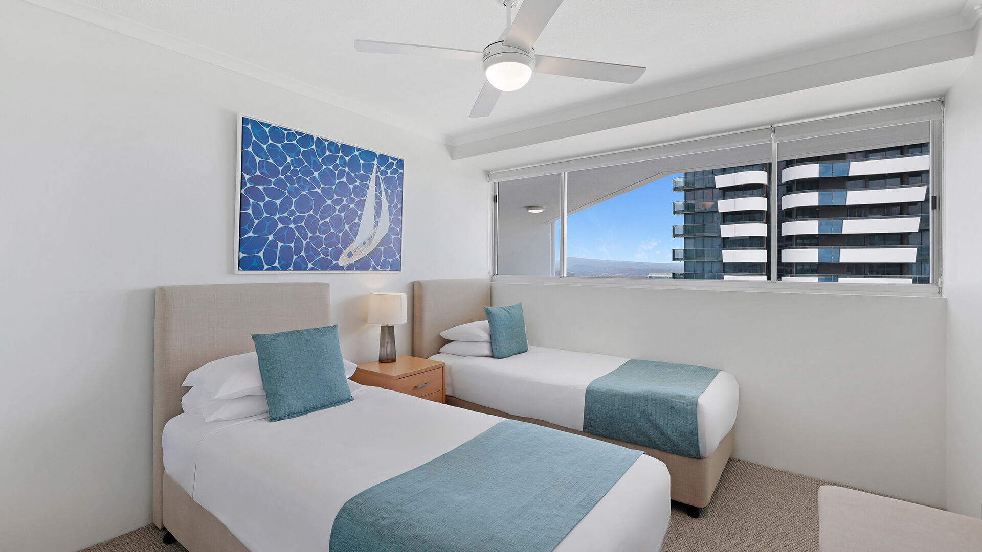 Twin bedroom of the 2 Bedroom Superior Ocean View Apartment featuring two single beds, teal accents, and a bright, coastal-inspired design.