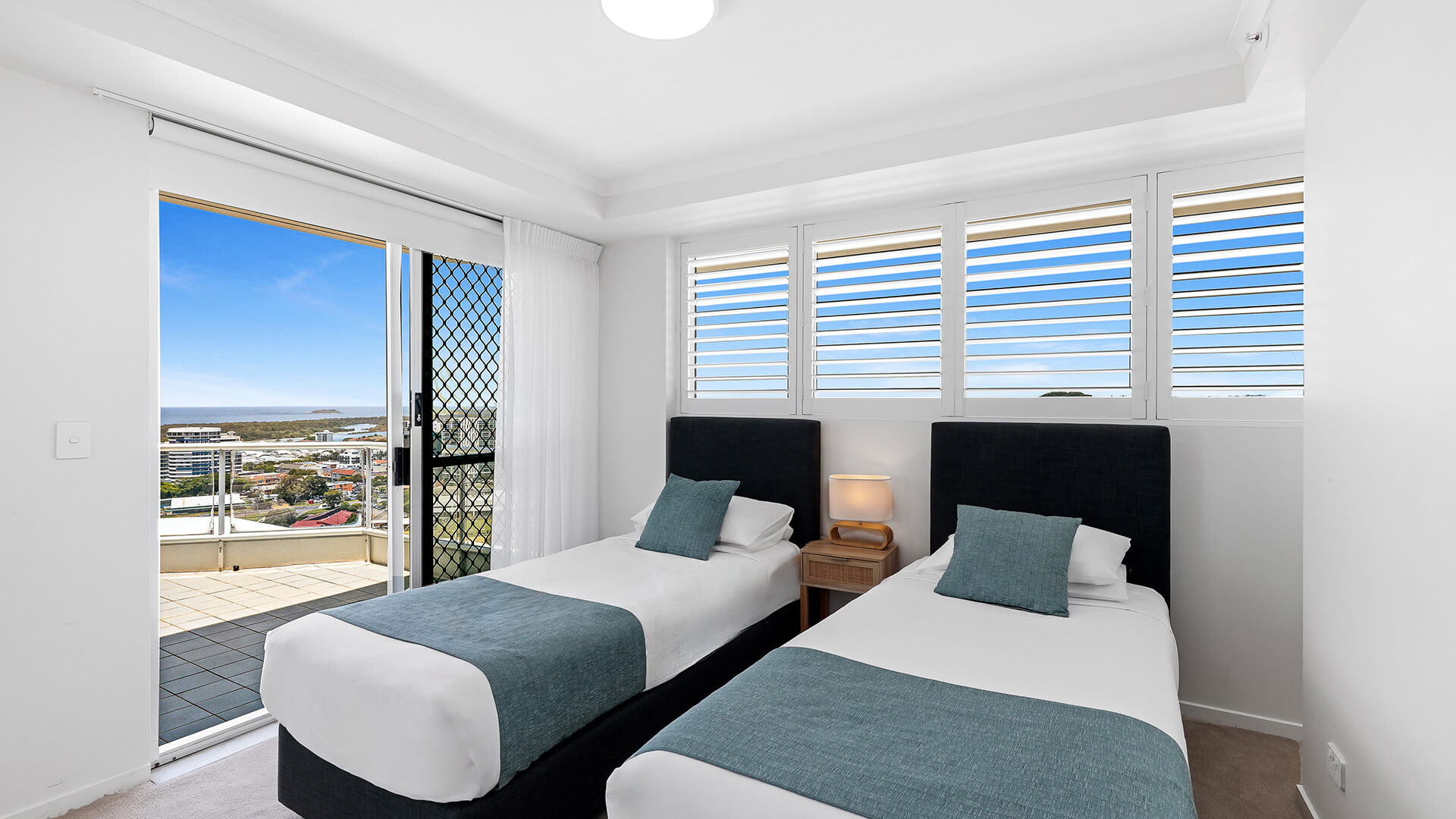 Twin bedroom in the Deluxe 3 Bedroom Ocean View Apartment at ULTIQA Points North, featuring two single beds and balcony access.