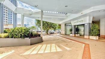 Covered driveway and entrance to ULTIQA Points North Coolangatta, featuring the reception signage, glass doors, and surrounding landscaped planters.
