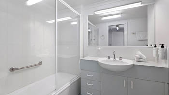 Bright bathroom with a shower-over-bath, large mirror, and ample vanity space.