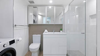 Modern bathroom of the 2 Bedroom Superior Ocean View Apartment with shower, vanity, toilet, and laundry facilities.