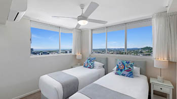 Twin bedroom in the Superior 3 Bedroom Ocean View Apartment featuring two single beds, soft coastal décor, and large windows with natural light.