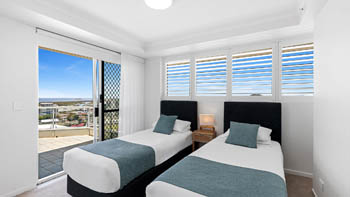 Twin bedroom in the Deluxe 3 Bedroom Ocean View Apartment at ULTIQA Points North, featuring two single beds and balcony access.