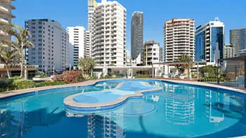 Outdoor resort-style swimming pool surrounded by sun loungers and city views at ULTIQA Beach Haven on Broadbeach.