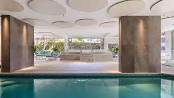 Heated indoor pool and spa area at ULTIQA Beach Haven on Broadbeach, featuring elegant tiled finishes, lounge seating, and natural light - perfect for year-round relaxation.