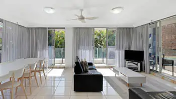 Spacious living and dining area with TV and floor-to-ceiling windows in the 2 Bedroom Apartment at ULTIQA Beach Haven on Broadbeach.