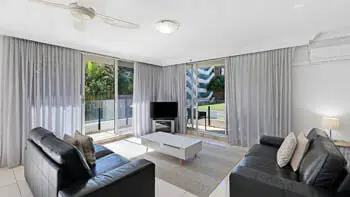 Living area with leather sofas and access to outdoor balcony in the 2 Bedroom Apartment at ULTIQA Beach Haven on Broadbeach.