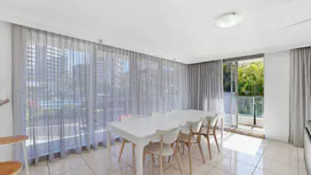 Dining area with seating for eight and large windows in the 2 Bedroom Apartment at ULTIQA Beach Haven on Broadbeach.