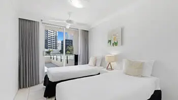 Second bedroom with two single beds and balcony access in the 2 Bedroom Apartment at ULTIQA Beach Haven on Broadbeach.