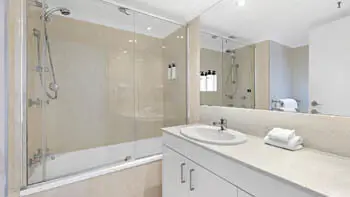 Bathroom in the 2 Bedroom Ocean View Apartment at ULTIQA Beach Haven on Broadbeach featuring a shower over bath and stone-top vanity.