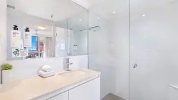 Modern bathroom in the 2 Bedroom Ocean View Apartment at ULTIQA Beach Haven on Broadbeach featuring a spacious walk-in shower, large mirror, and sleek vanity with fresh towels and amenities.