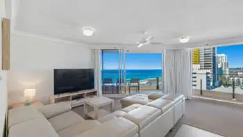 Living room in the 2 Bedroom Ocean View Apartment at ULTIQA Beach Haven on Broadbeach with large sectional sofa, flat-screen TV, and ocean-facing balcony.