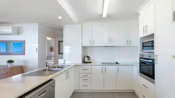 Fully equipped kitchen in the 2 Bedroom Ocean View Apartment at ULTIQA Beach Haven on Broadbeach with modern appliances and ample storage.