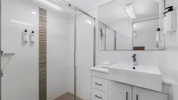Modern bathroom at ULTIQA Beach Haven on Broadbeach featuring a walk-in shower, large vanity, and mirrored cabinetry with complimentary amenities.
