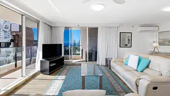 Standard 2 Bedroom Ocean View Apartment with Living room and ocean views at ULTIQA Beach Haven on Broadbeach, featuring leather lounges, a flat-screen TV, and natural light.