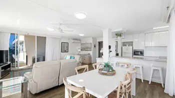 Standard 2 Bedroom Ocean View Apartment with open-plan living, dining, and kitchen area at ULTIQA Beach Haven on Broadbeach, featuring modern furnishings, a white interior, and natural light.