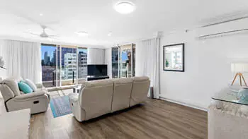 Standard 2 Bedroom Ocean View Apartment with spacious living room, leather lounges and flat-screen TV at ULTIQA Beach Haven on Broadbeach, featuring large windows and city views.