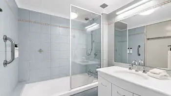 Main bathroom in the Standard 2 Bedroom Ocean View Apartment at ULTIQA Beach Haven on Broadbeach, featuring a combined shower and bathtub, large mirror, and tiled walls.