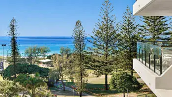 Ocean views from ULTIQA Beach Haven on Broadbeach with parklands, towering pine trees, and turquoise water visible from the resort.