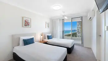 Second bedroom in the Premium 2 Bedroom Ocean View Apartment at ULTIQA Beach Haven on Broadbeach, featuring two single beds and ocean-facing balcony access.
