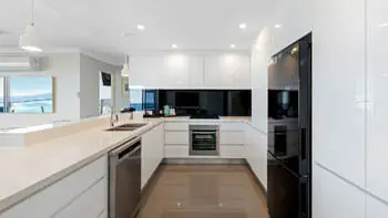 Contemporary kitchen featuring sleek white cabinetry, stone benchtops, and premium appliances.