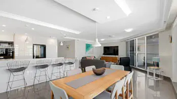 Spacious dining and living featuring a breakfast bar, modern lighting, and private balcony access.