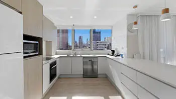 Modern fully equipped featuring sleek cabinetry, stainless steel appliances, and large window with city views.