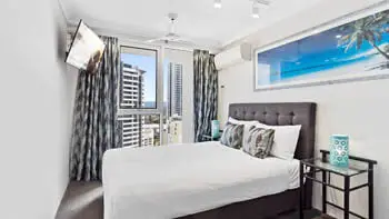 Second bedroom with a king bed and a TV in the corner at ULTIQA Beach Haven on Broadbeach.