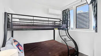 Third bedroom with white walls, bunk beds and a window at ULTIQA Beach Haven on Broadbeach.