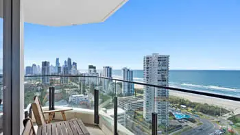 View of Broadbeach from the balcony at ULTIQA Beach Haven on Broadbeach with a nice wooden outside furniture set of a table and two chairs.