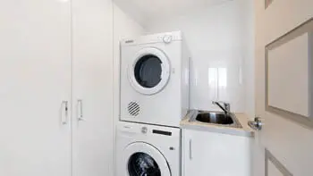 Fully equipped laundry in the Sub Penthouse at ULTIQA Beach Haven on Broadbeach, featuring a washer, dryer, and sink.