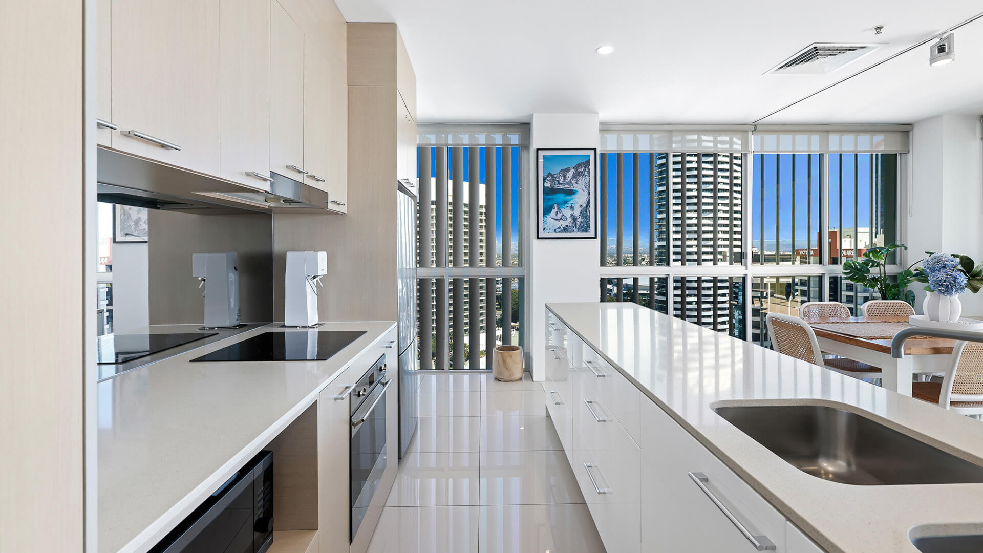 Modern kitchen with island bench and dining area in 2 Bedroom Gold Coast View Suite at ULTIQA Air on Broadbeach.