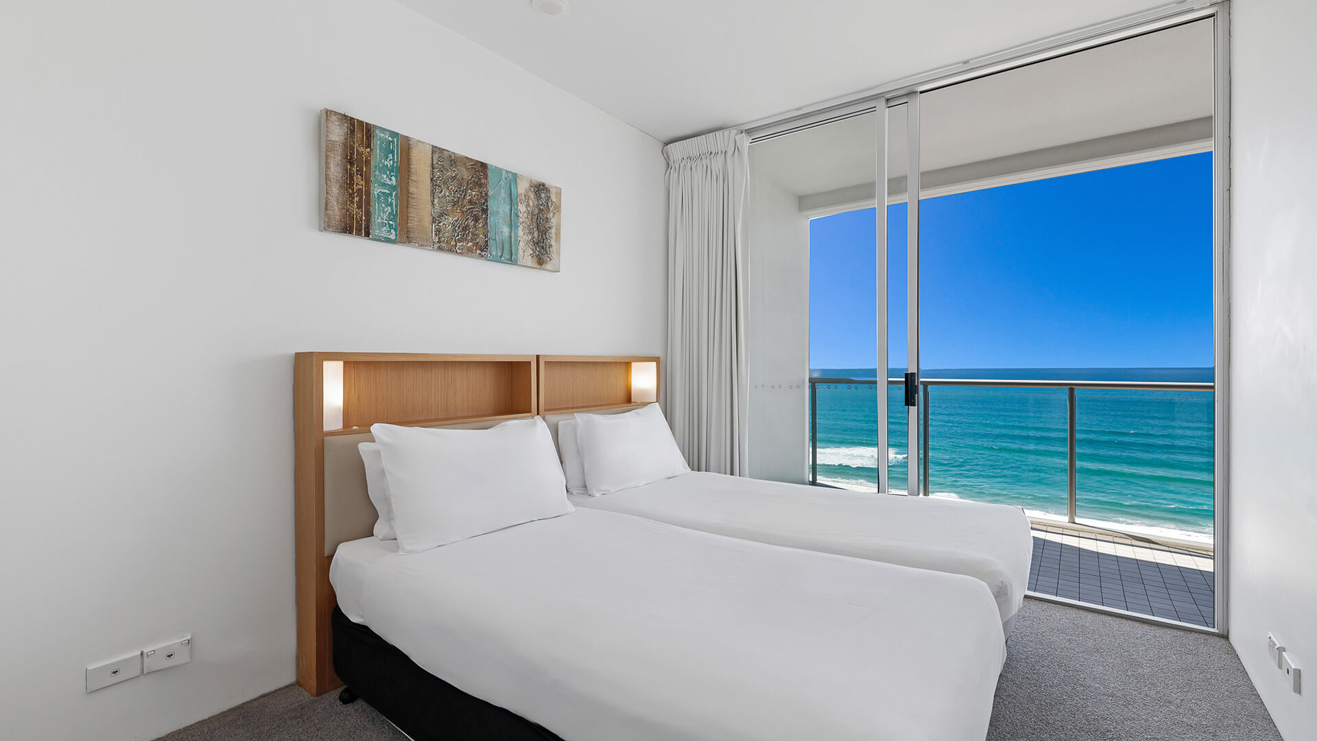 Bedroom with twin beds and private balcony overlooking the ocean in 2 Bedroom Ocean View Apartment at ULTIQA Air on Broadbeach.