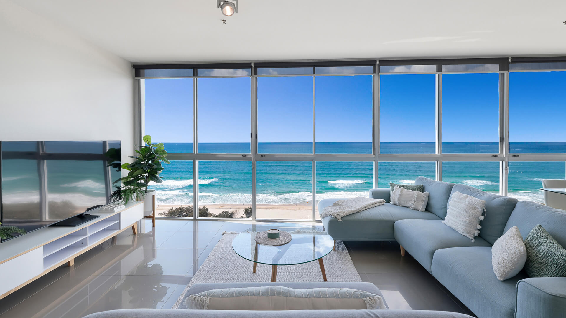 Living area with sofa and floor-to-ceiling windows showcasing ocean views in 2 Bedroom Ocean View Suite at ULTIQA Air on Broadbeach.