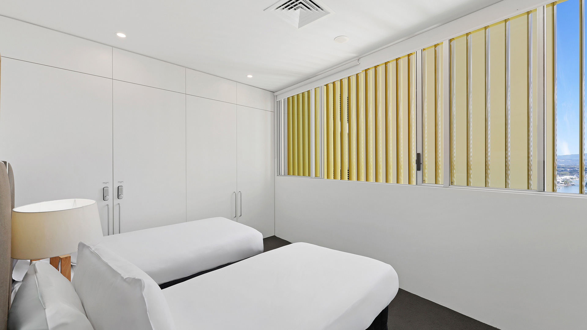 Third bedroom in 3 Bedroom Ocean View Apartment at ULTIQA Air on Broadbeach with two single beds and built-in wardrobes.