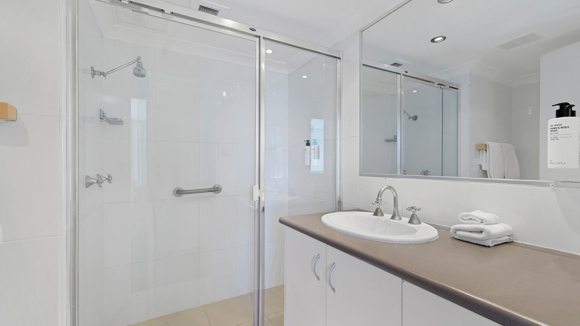 Main bathroom in the Standard 2 Bedroom Ocean View Apartment at ULTIQA Beach Haven, featuring a glass shower, large mirror, and vanity.