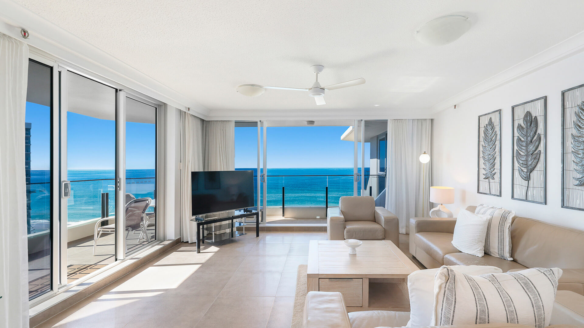 Light-filled living room in the 2 Bedroom Ocean View Apartment at ULTIQA Beach Haven with coastal décor, comfortable leather seating, and uninterrupted ocean views through floor-to-ceiling windows.