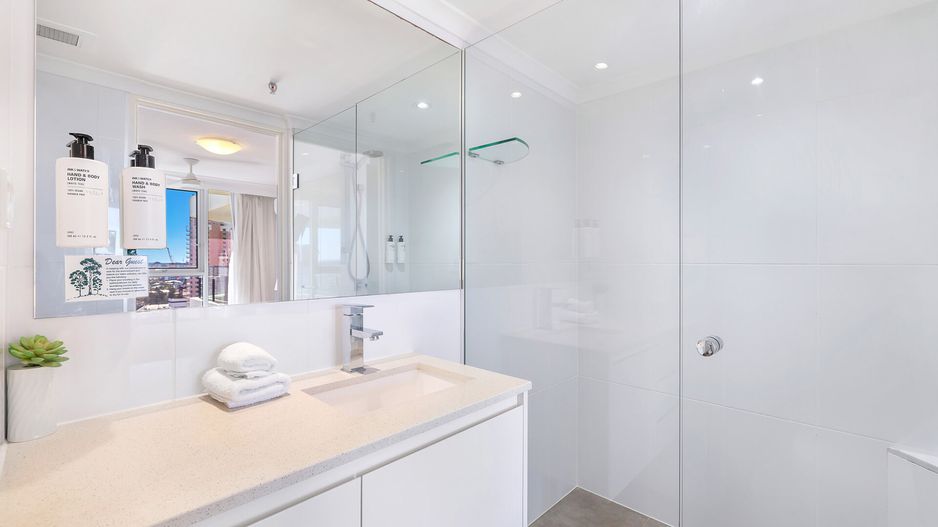 Modern bathroom in the 2 Bedroom Ocean View Apartment at ULTIQA Beach Haven featuring a spacious walk-in shower, large mirror, and sleek vanity with fresh towels and amenities.