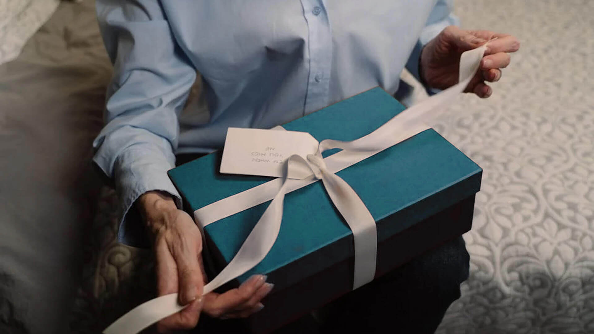 Person holding an aqua green gift box with a white ribbon, promoting the perfect gift vouchers for any occasion.