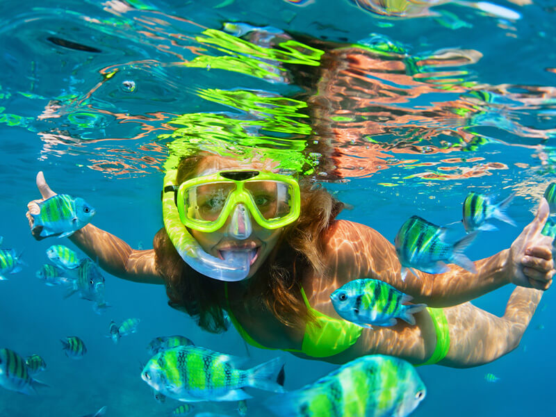 Woman snorkelling with tropical fish in clear Fiji waters.