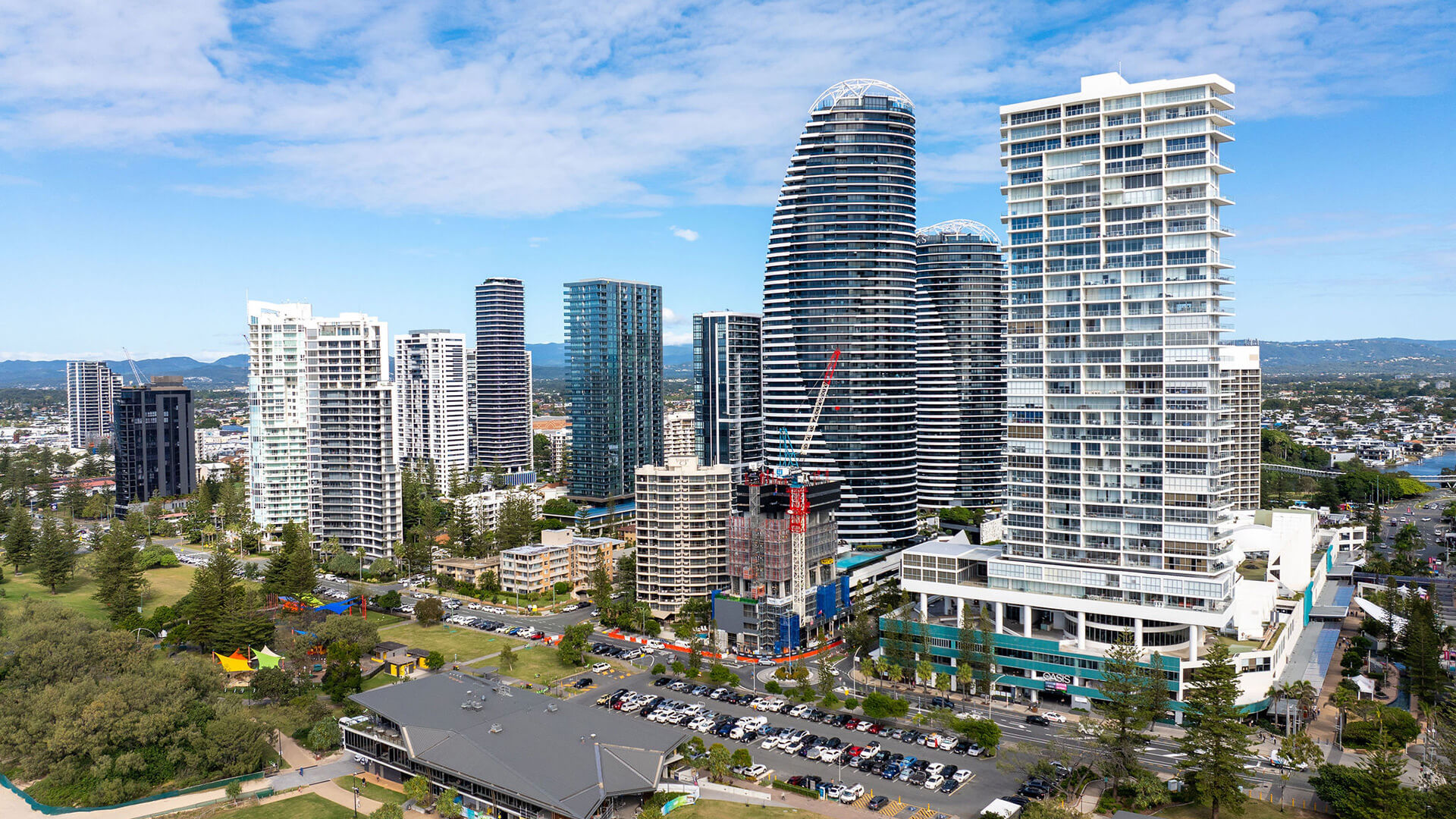 Arial view from ULTIQA Air on Broadbeach overlooking city high-rises, green parklands, and the beach under a partly cloudy sky.