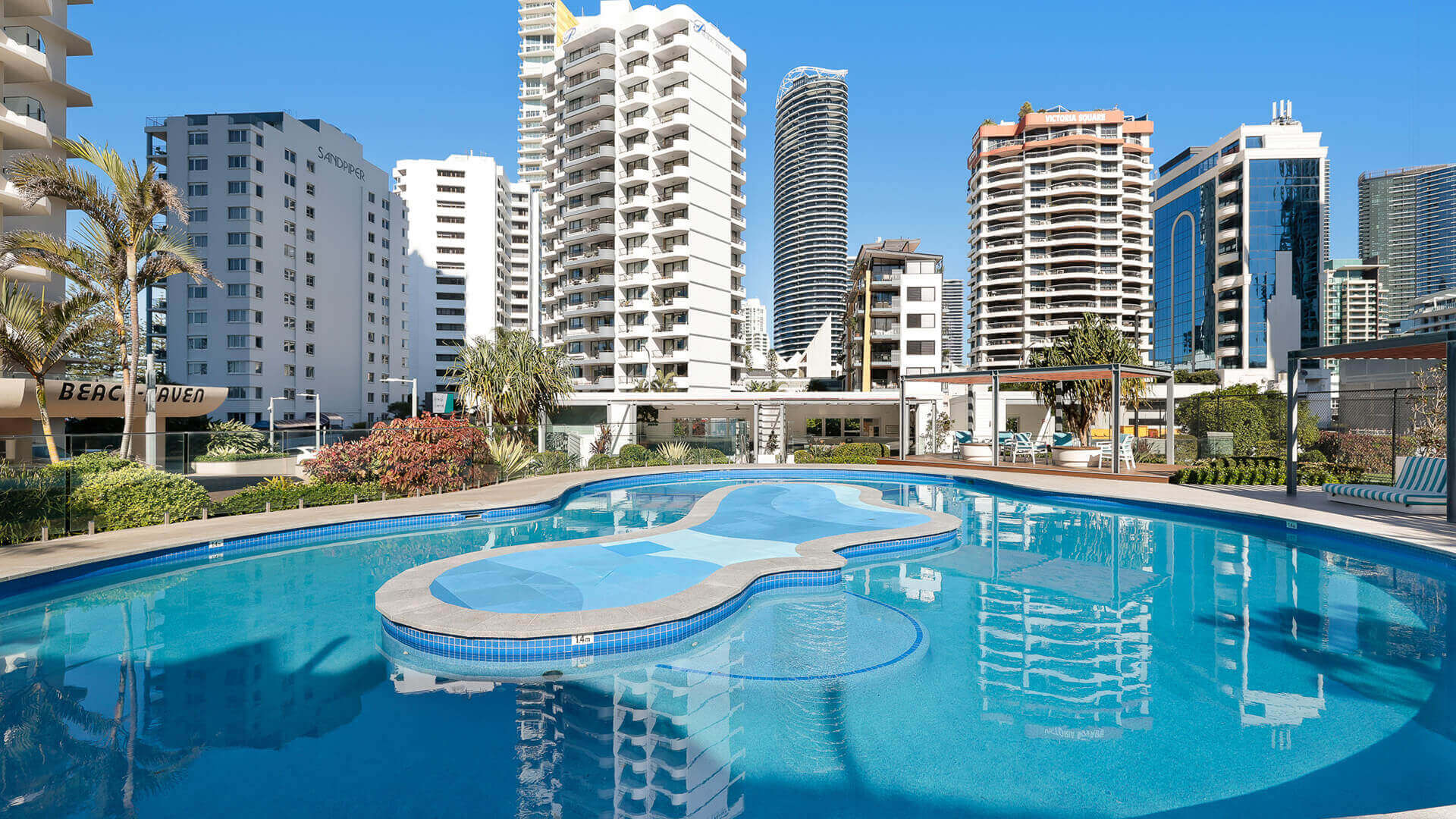 Outdoor resort-style swimming pool surrounded by sun loungers and city views at ULTIQA Beach Haven.
