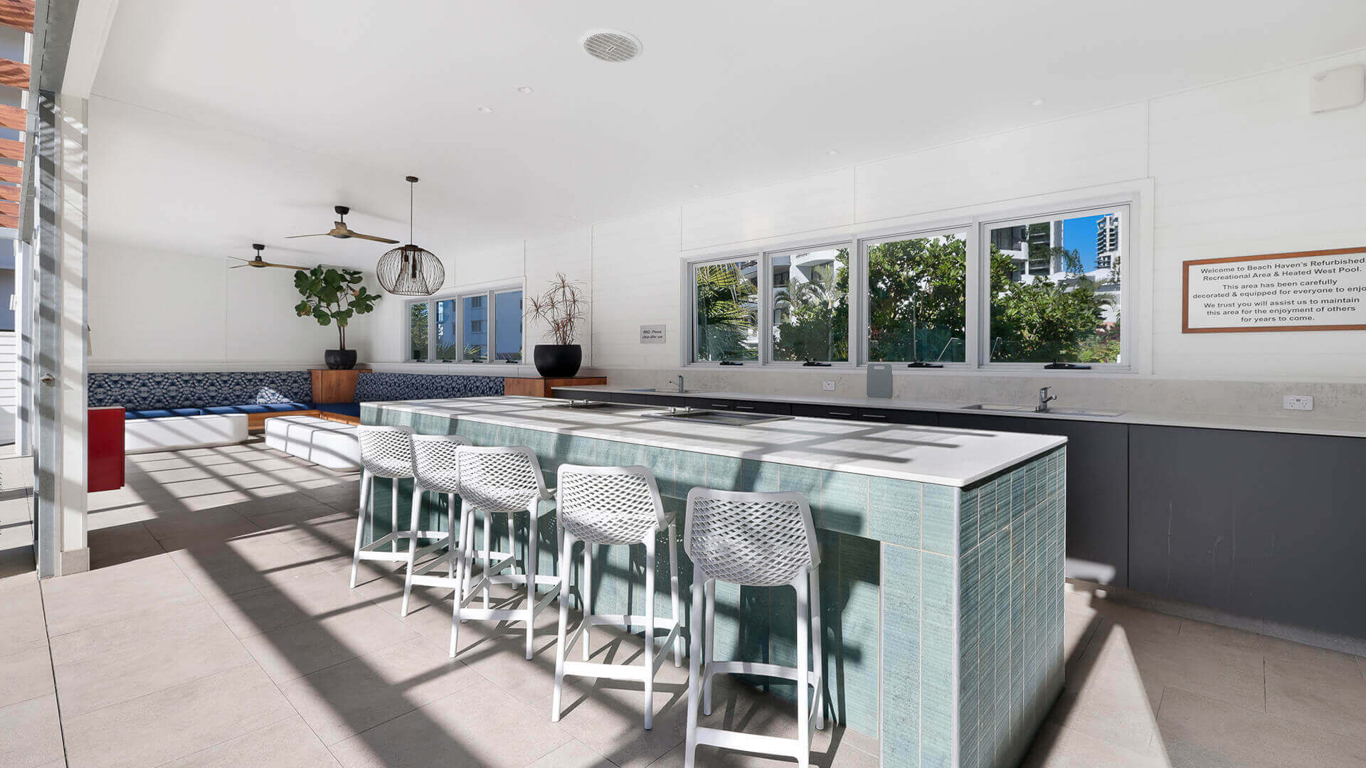Guest BBQ and recreation area at ULTIQA Beach Haven featuring a tiled island bench, bar seating, modern cooking facilities, and built-in lounge seating ideal for casual outdoor dining.