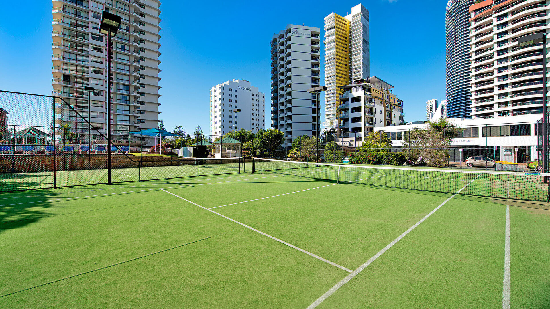 Outdoor tennis court at ULTIQA Beach Haven surrounded by high-rise buildings, offering guests a space for recreational play in the heart of the Gold Coast.
