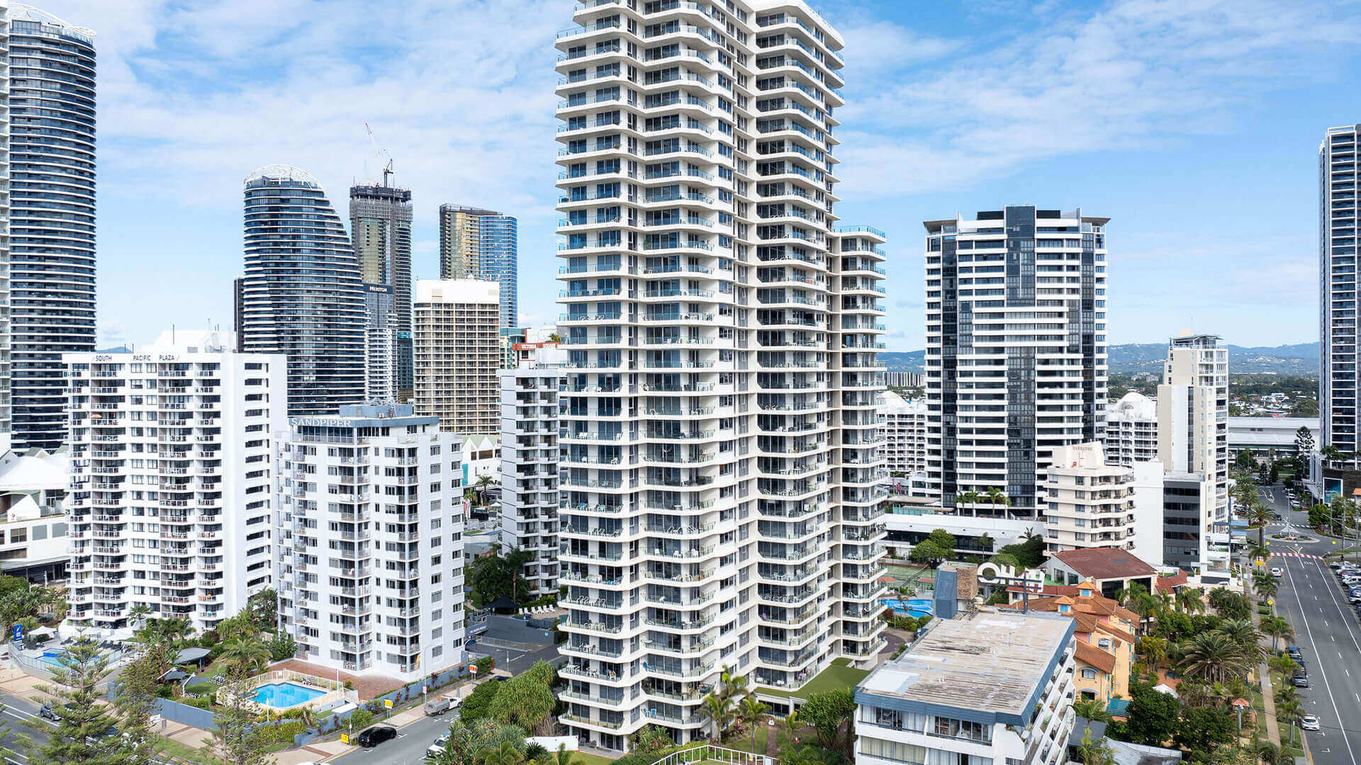 Aerial view of ULTIQA Beach Haven surrounded by high-rise buildings, with resort pools visible and just moments from the Gold Coast beachfront.
