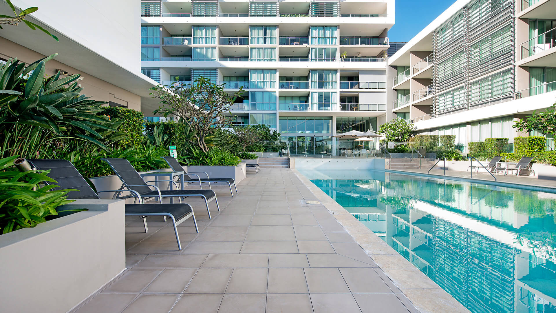 Outdoor lap pool with sun loungers at ULTIQA Freshwater Point Resort, Broadbeach.