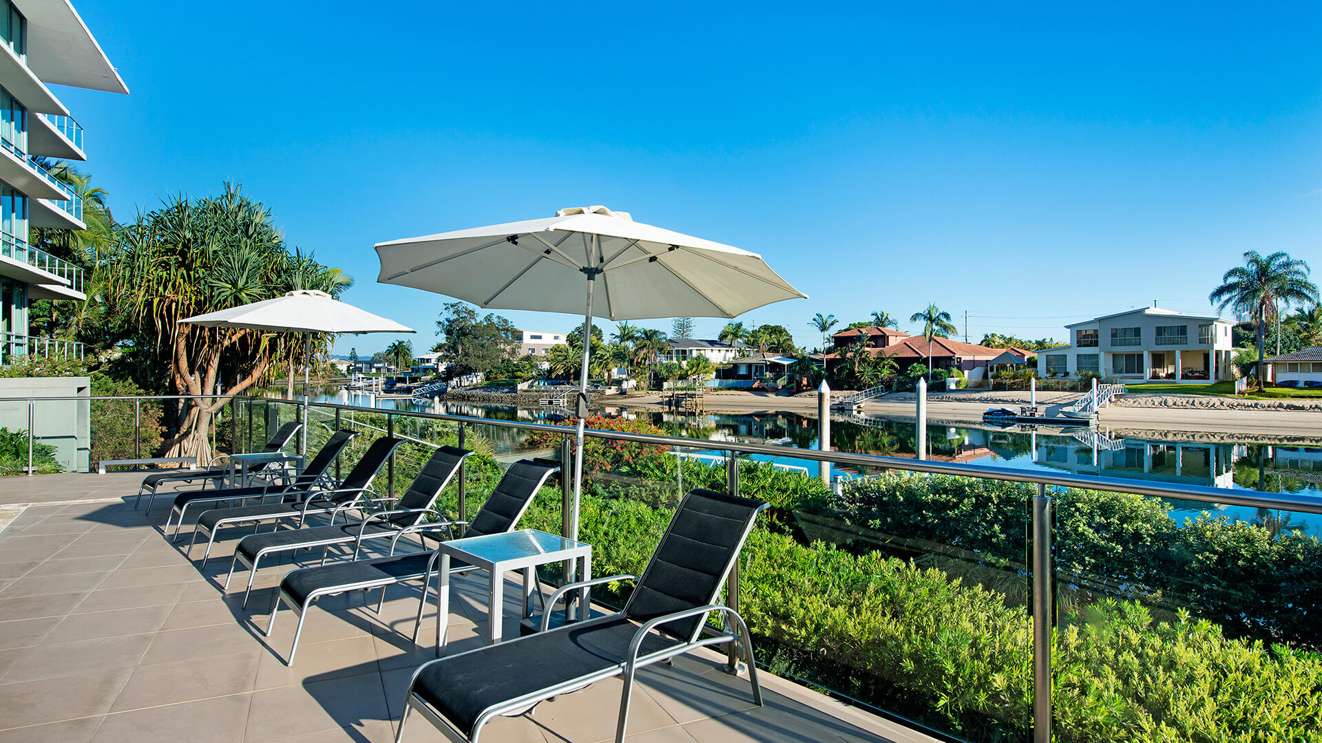 Sun loungers with umbrellas overlooking the water at ULTIQA Freshwater Point Resort.