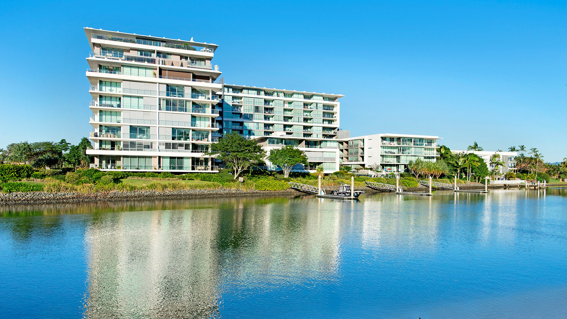 ULTIQA Freshwater Point Resort viewed from across the river, showcasing its modern waterfront buildings.